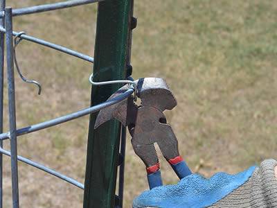 A worker is bending the silt fence wire mesh with a pair of fencing pliers.